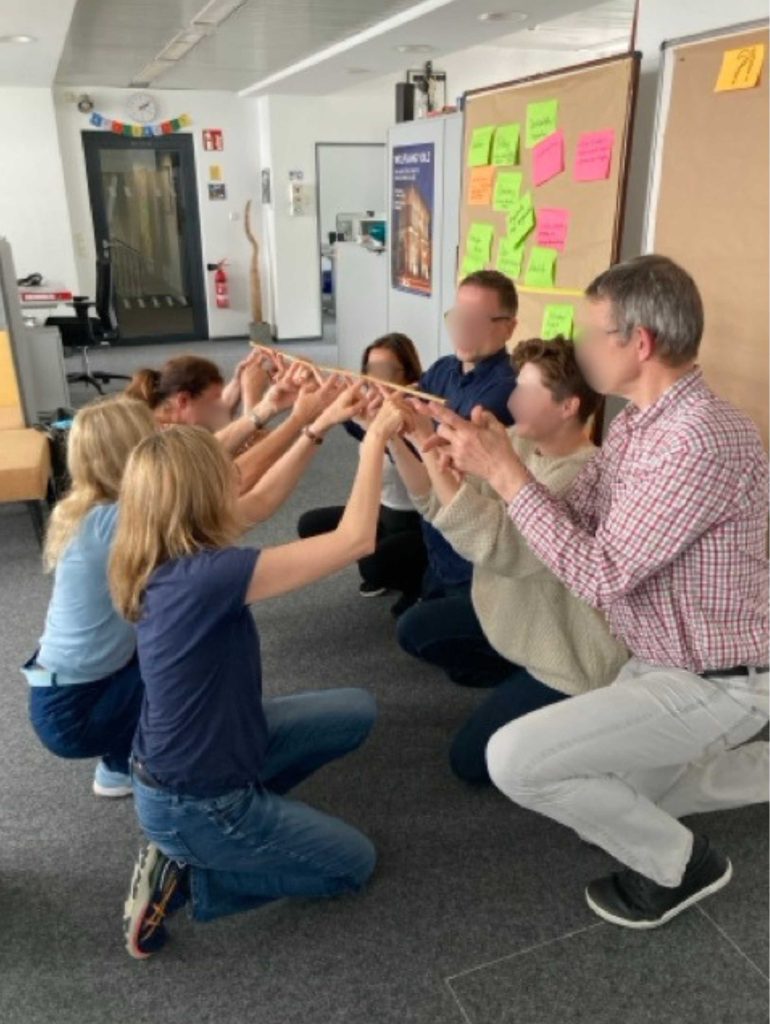 Menschen halten einen Stock bei einem Teambuilding bzw. Teamcoaching in Köln fest
